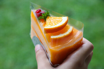Hand holding orange cake jam bakery fresh fruit topping individually wrapped, pack piece by piece