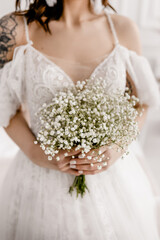 The bride in a white dress with a bouquet of gypsophila