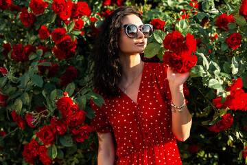 Beautiful caucasian girl with curly brunet hair in a trendy vintage red dress with polka dots with...