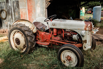 a vintage old antique res and gray tractor at a rural farm