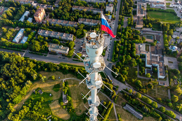 Aerial view of a meteorological mast with a flag of Russia and a panorama of urban development in the city of Obninsk, Russia. June 2021