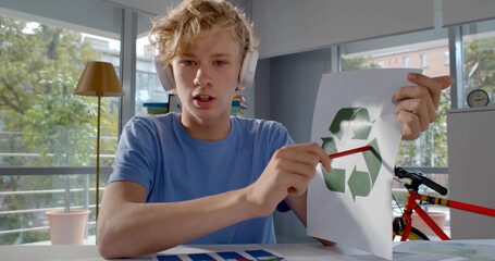 Teen boy in headphones discussing recycling project having online lesson