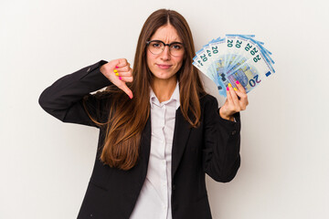 Young caucasian business woman holding banknotes isolated on white background showing a dislike...