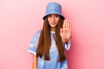 Young caucasian woman isolated on pink background standing with outstretched hand showing stop sign, preventing you.