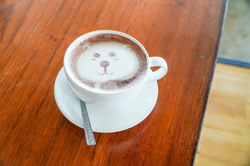 Latte art in the shape of a bear on a coffee table on a wooden table.