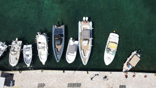 KASSIOPI, CORFU, GREECE - AUGUST 7, 2021: Aerial drone view over modern motor boats moored in Old Port. Kassiopi was historically a small traditional fishing village.