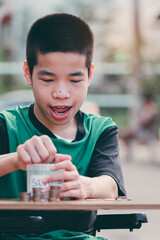 Smart asian disabled child on wheelchair put coins in diy piggy bank with smiling face saving money for education,Learning in the future, Happy disabled kid concept.