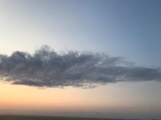 Blue and orange sunset sky with sun rays, dark clouds.