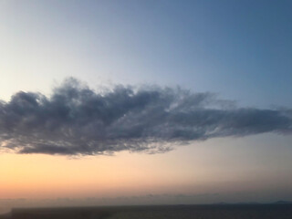 Blue and orange sunset sky with sun rays, dark clouds.