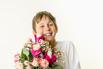 A bouquet of flowers in the hands of a smiling eight-year-old boy. Greeting card mockup with copy space