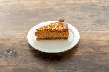 Delicious portion of dulce de leche cake with chopped almonds on white plate and vintage table