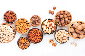 Nuts in bowls. Almonds, hazelnuts, walnuts and other. Healthy food snack mix on white table, top...