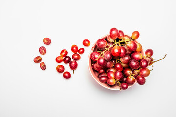 Clusters of claret color dessert grapes in pink bowl on white table