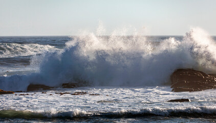 High storm wave with foam and spray breaks on the shore.