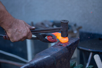 a blacksmith hits the iron on the anvil, Bistrita, Romania, August, 2021