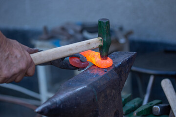 a blacksmith hits the iron on the anvil, Bistrita, Romania, August, 2021