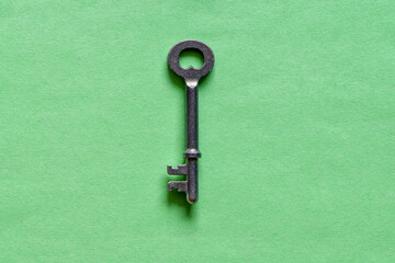 Old steel key laying on the green background