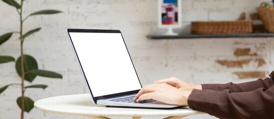 Woman using or typing laptop outside cafe restaurant with natural. Laptop computer on white desk and white blank on screen.