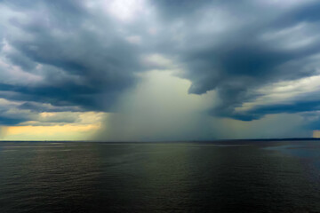 Dramatic dark seascape. Storm clouds and rain over the sea, cloudy weather, shower