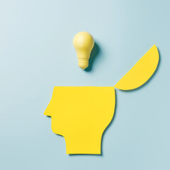Yellow paper head silhouette with an open mind full of mindful ideas on pastel blue background....