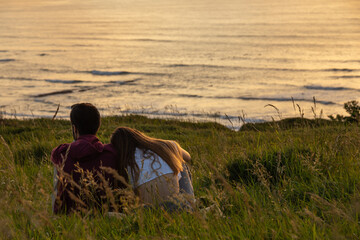 sweet young couple enjoying sunset together in front of the sea