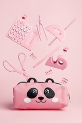 Pink panda pencil case with school equipment flying and levitating on pastel pink background. Creative back to school concept.