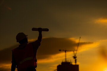 silhouette of engineer and construction site background at sunset