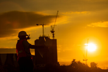 Fototapeta na wymiar silhouette of engineer and construction site background at sunset