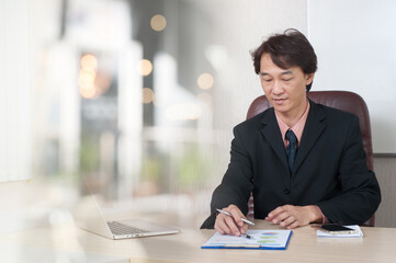  Asian businessman sits in his office working on the company's financial reports.