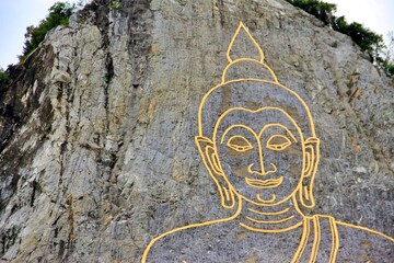 Buddha image engraved into the rock face using lasers outlined using gold