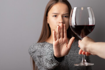 refuse alcohol, stop liquor, teenager shows a sign of rejection of wine with her hand - obrazy, fototapety, plakaty