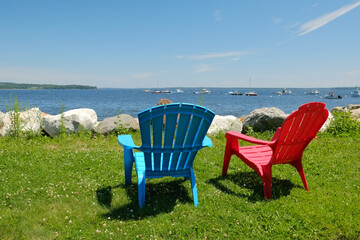 Relaxing by the bay in coastal New England on a couple of colorful adirondack chairs on a summers day