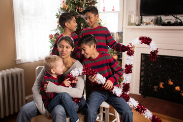Indoor casual Christmas portrait of five siblings in matching clothing talking and having fun holding giant candy_canes with tree in background