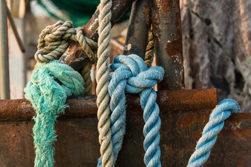 Knotted blue rope laying over the side of a rusting frame and hull of a deep sea trawler