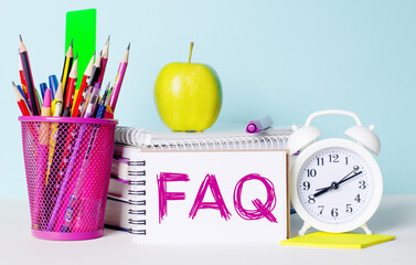 On a light table there are books, stationery, a white alarm clock, an apple. Next to it is a...
