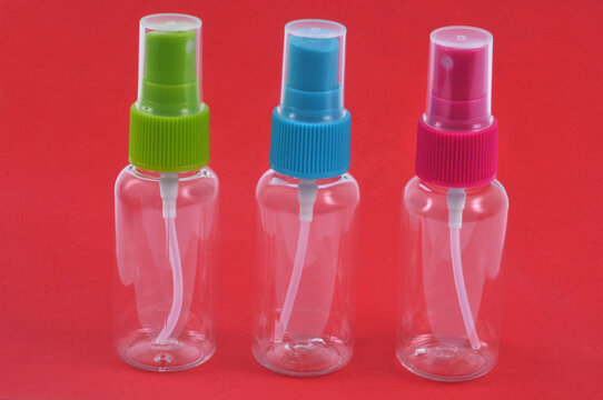 Vaporisateurs en plastique vides en gros plan sur fond rouge