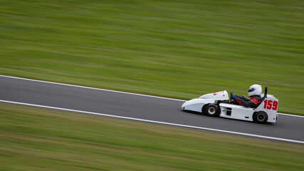 A panning shot of a racing kart as it circuits a track.