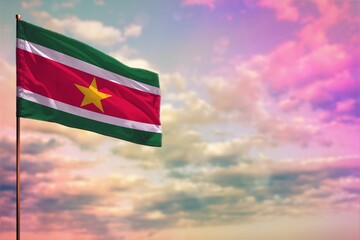 Fluttering Suriname flag mockup with the space for your content on colorful cloudy sky background.