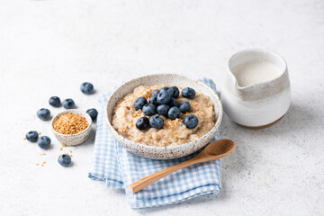 Vegan oatmeal porridge with blueberries and flax seeds on natural grey background. Healthy eating,...