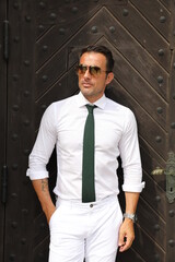 Bardzo przystojny, elegancki mężczyzna w białej koszuli i zielonym krawacie i okularach...