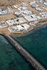 Fototapeta na wymiar Fotografía aérea de espigón portuario y pueblo de la Caleta del Sebo en la isla de La Graciosa, Canarias
