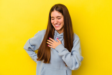 Young caucasian woman isolated on yellow background laughing keeping hands on heart, concept of happiness.