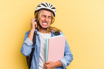 Young caucasian student woman wearing a bike helmet isolated on yellow background  covering ears with hands.