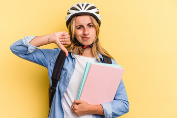 Young caucasian student woman wearing a bike helmet isolated on yellow background  showing a dislike gesture, thumbs down. Disagreement concept.