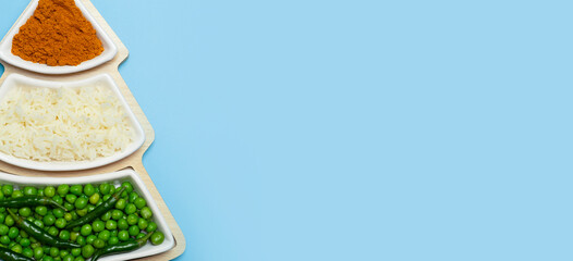 Indian flag in the shape of a new year christmas tree made from food background. Basmati rice, curry, green peas and chili peppers in the colors of the Indian flag and Christmas tree on a blue