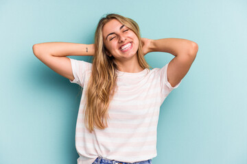 Young caucasian blonde woman isolated on blue background  feeling confident, with hands behind the head.