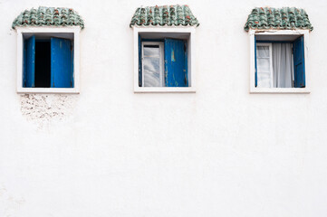 Fototapeta na wymiar White house facade with windows / White house facade with three blue windows.