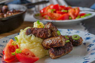 Cevapcici with mashed potatoes and tomato salad