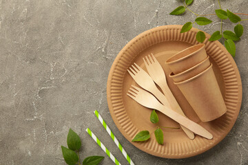 Eco friendly disposable dishes with green leaves on grey background. Zero waste, eco friendly,...