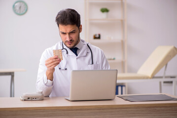 Young male doctor holding pills in the clinic